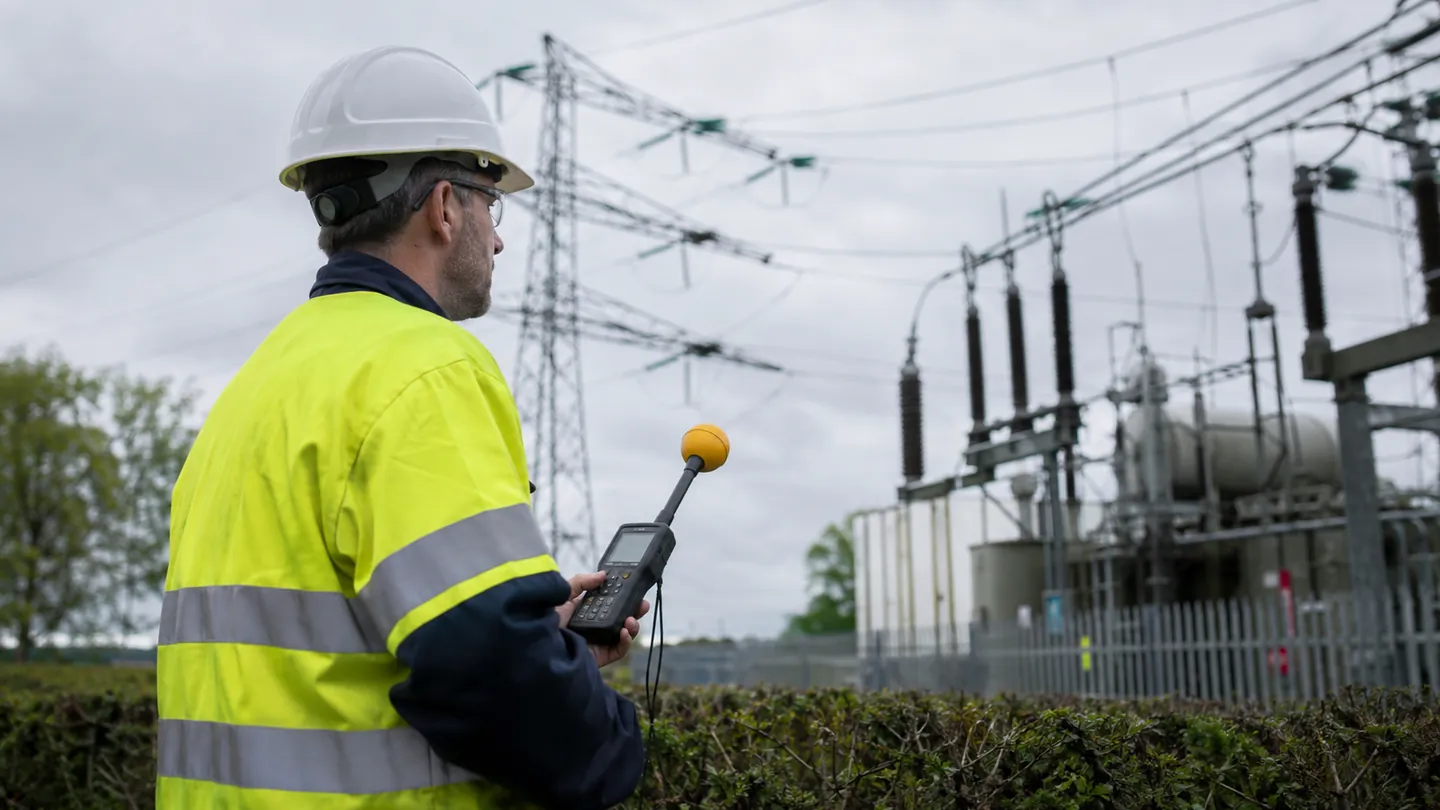 Consultant carrying out electromagnetic field measurements near electrical infrastructure.
